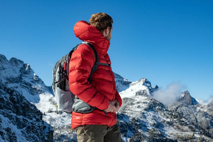 کاپشن پر کوهنوردی قرمز بر تن کوهنورد مرد در ارتفاعات